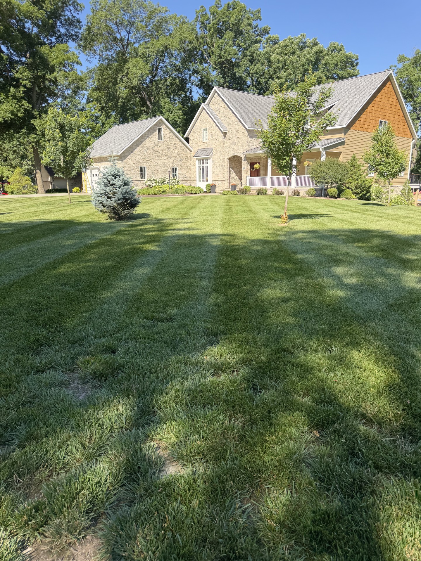 Freshly mowed striped lawn in front of a stone home